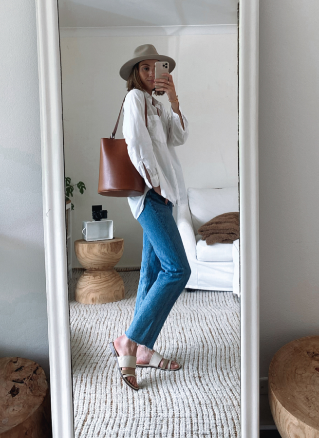 white shirt outfit with blue jeans, hat and brown bucket bag